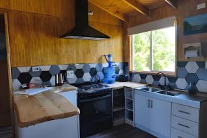 a kitchen with black and white appliances and a window at Casa completa en Carretera Austral KM 23 con Fibra Óptica in Puerto Montt