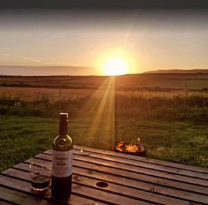 a bottle of wine sitting on a picnic table with a fire at Two Peas in a Pod in Holyhead