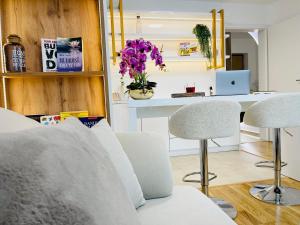 a living room with white furniture and purple flowers at SOL LUX Tuzla in Tuzla