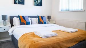 a bedroom with a large bed with two towels on it at 3BR House Near Cardiff Bay City Centre and Stadium with Free Parking in Cardiff