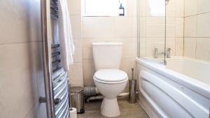 a bathroom with a white toilet and a bath tub at 3BR House Near Cardiff Bay City Centre and Stadium with Free Parking in Cardiff +23 photos