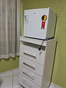 a white dresser with a refrigerator on top of it at Pousadinha só in Foz do Iguaçu +2 photos