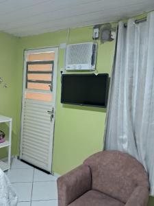 a room with a chair and a television and a window at Pousadinha só in Foz do Iguaçu