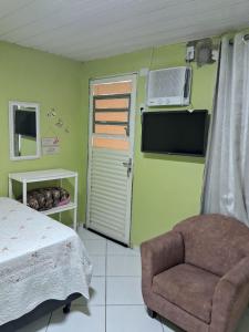 a bedroom with a bed and a chair and a tv at Pousadinha só in Foz do Iguaçu