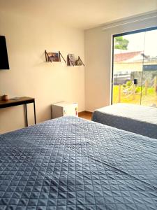 a bedroom with two beds and a window at Suíte aMAR in São Pedro da Aldeia