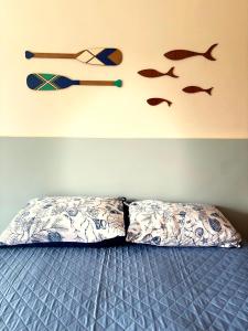 a bed with two pillows and fish on the wall at Suíte aMAR in São Pedro da Aldeia