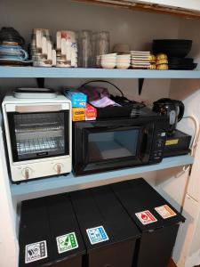 a microwave and a toaster oven on a shelf at 一棟貸し古民家月の桃 in Motobu