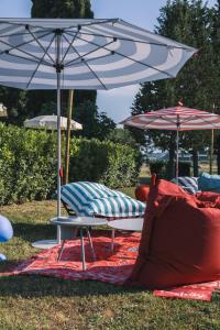 two umbrellas and chairs on a blanket in the grass at La Vecchia cantina Guzzardi in Lari