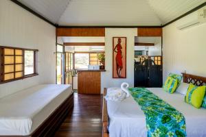 a bedroom with two beds and a kitchen at Moorea Maatea Tahatai Lodge in Moorea