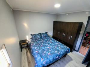 a bedroom with a bed with a blue comforter at Arriendo en Valdivia cabañas in Valdivia