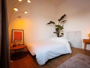 a bedroom with a white bed with a plant on the wall at LOFT-54 -Exclusive Apartment with Terrace in Zwevegem
