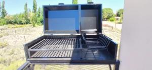 an empty grill with a chair in a field at El Rincon del Descanso in General Alvear
