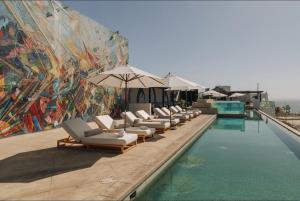 a row of lounge chairs sitting next to a swimming pool at Hotel El Ganzo - Adults Only in San José del Cabo