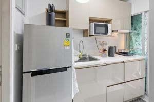 a white kitchen with a refrigerator and a sink at Spacious 1BR wSofa Bed Pool Gym 1Gbps Wi-Fi in Kathu