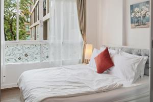 a bed with white sheets and red pillows next to a window at Spacious 1BR wSofa Bed Pool Gym 1Gbps Wi-Fi in Kathu