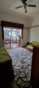 a room with a stone floor with tables and a ceiling fan at Chalet para desconectar in Piriápolis