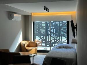 a bedroom with a bed and a chair and a window at Nogales Apartamentos in Mar del Plata +129 photos