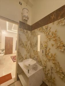 a bathroom with a sink and flowers on the wall at Arohan stay in Ayodhya