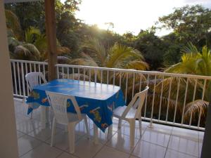 a table and chairs on a balcony with palm trees at Frédovacances logement iGloo-LOVE in Rivière-Pilote