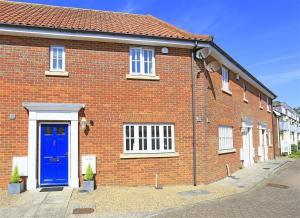 a brick house with a blue door on a street at 3 Bed in Southwold oc-kit in Reydon