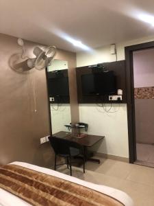 a bedroom with a bed and a table and a television at Hotel Confirm Inn Kota in Kota