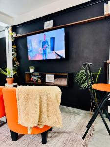 a living room with an orange chair and a tv at Studio Vellae in Corinthe