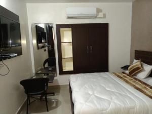 a bedroom with a bed and a desk and a window at Hotel Confirm Inn Kota in Kota
