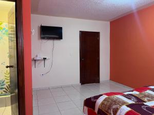 a bedroom with a bed and a television on a wall at Hostal Villa Franca in Ibarra