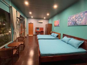 a room with two beds and a table and chairs at Melalueca tây ninh in Tây Ninh