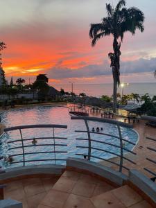 a swimming pool with a sunset in the background at Apartamento en Tonsupa - Torresol Tropical in Tonsupa