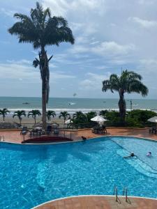 a large swimming pool with palm trees and the ocean at Apartamento en Tonsupa - Torresol Tropical in Tonsupa +15 photos