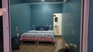 a bedroom with a bed in a blue wall at Refugio del Mar in Puerto Escondido