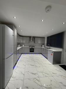 a large white kitchen with a large tile floor at Luxury modern guest house in Birmingham
