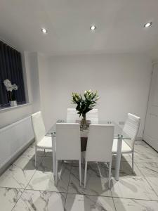 a dining room table with white chairs and a vase of flowers at Luxury modern guest house in Birmingham +9 photos