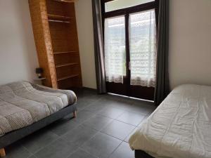 a bedroom with two beds and a large window at La villa Madelon in Cilaos +2 photos