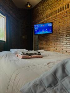 a bedroom with a bed with a tv on a brick wall at El Resguardo in San Luis