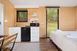 a bedroom with a bed and a kitchen with a microwave at Wombat Hideaway by Tiny Away in Laguna