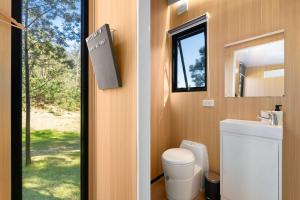 a bathroom with a toilet and a sink and a window at Wombat Hideaway by Tiny Away in Laguna