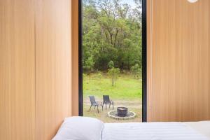 a bedroom with a window looking out at a yard at Wombat Hideaway by Tiny Away in Laguna +16 photos