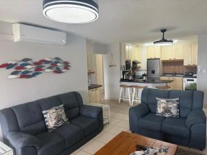a living room with two blue couches and a kitchen at 37 Laguna La Crete in Margate +9 photos