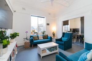 a living room with blue chairs and a table at Manly Beach Guesthouse in Sydney
