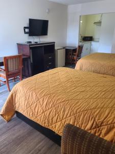 a hotel room with two beds and a desk and a television at Relax Inn And Suites in El Cajon