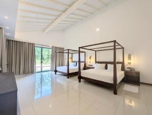 two beds in a room with white walls at Pinthaliya Resort in Sigiriya