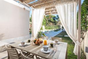 an outdoor dining room with a table and a view of a yard at Klio by Vintage Travel in Agios Georgios