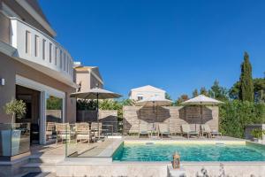 a swimming pool with chairs and umbrellas next to a house at Erato by Vintage Travel in Tsoukalades