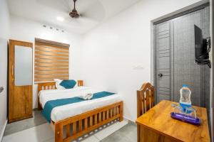 a bedroom with a bed and a table and a television at FORA Inn in Cochin