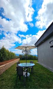 a table and chairs with an umbrella on the grass at LUZ DE LUNA mesa de los santos house in Los Santos