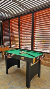 a pool table sitting in front of a room with windows at LUZ DE LUNA mesa de los santos house in Los Santos