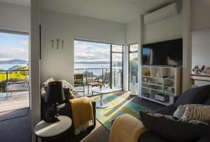 a living room with a couch and a television at W91 Stylish, Modern, Beach view in Tutukaka