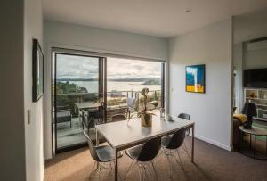 a living room with a table and chairs and a balcony at W91 Stylish, Modern, Beach view in Tutukaka
